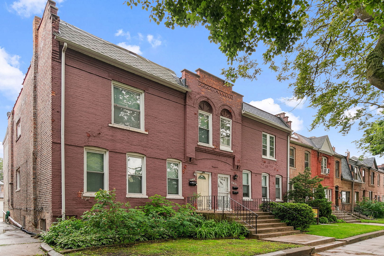 a front view of a multi story residential apartment building with yard and green space