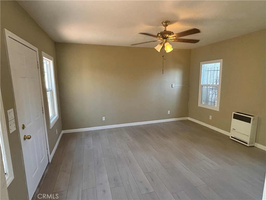 an empty room with wooden floor fan and windows