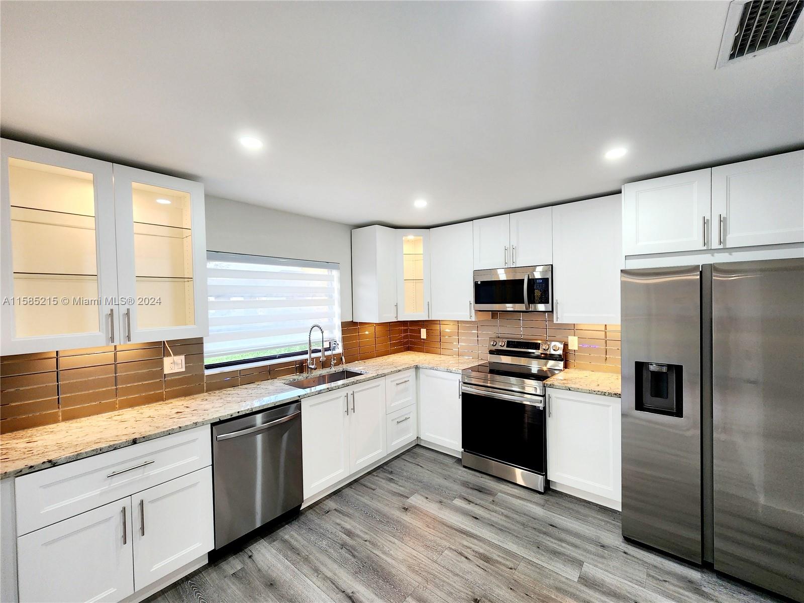 a kitchen with stainless steel appliances granite countertop a stove a sink and a refrigerator