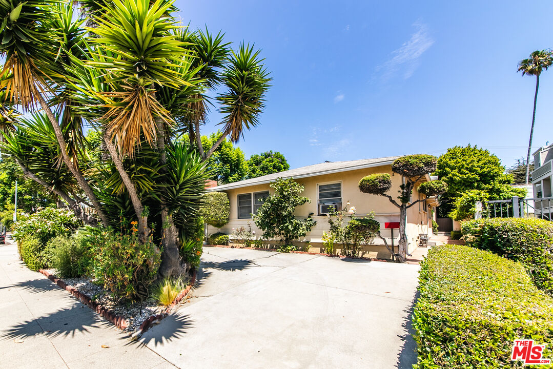 a front view of a house with a yard and potted plants