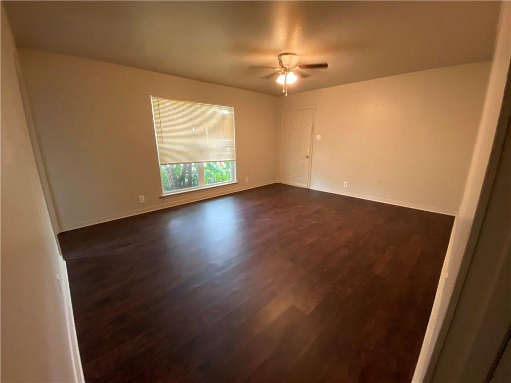 an empty room with wooden floor fan and window