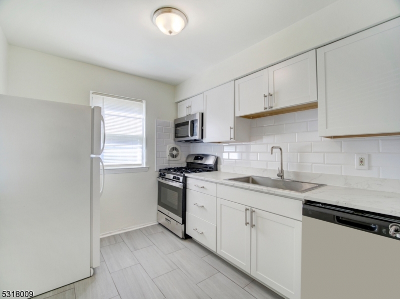 a kitchen with granite countertop white cabinets sink and stainless steel appliances