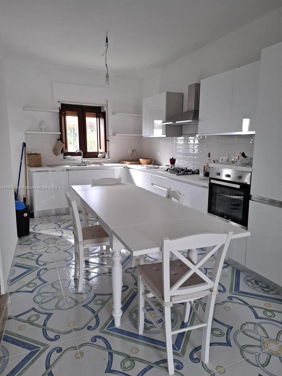 a kitchen with kitchen island a dining table chairs and a sink