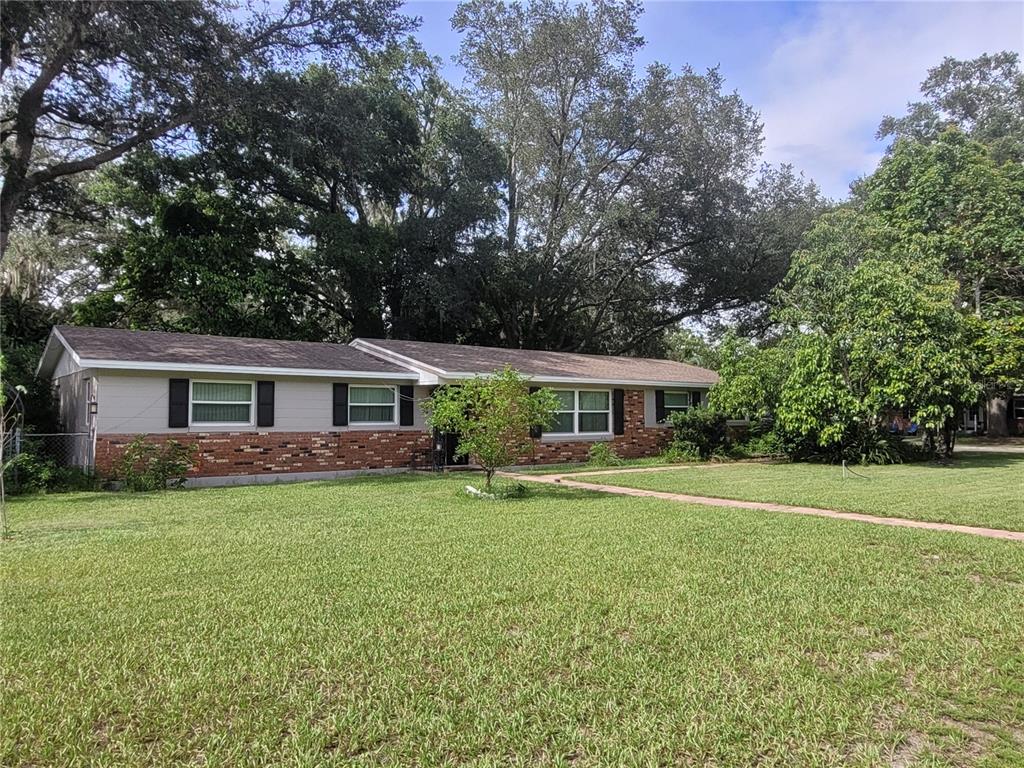 a view of a house with a big yard and large trees