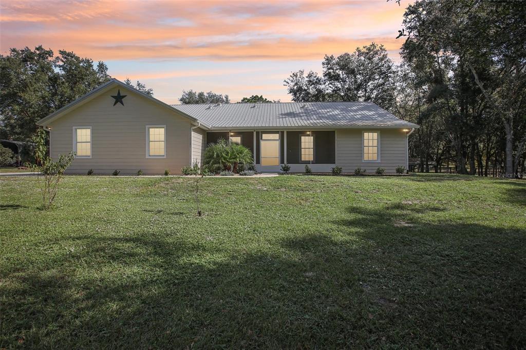 a house that is sitting in the grass with large trees