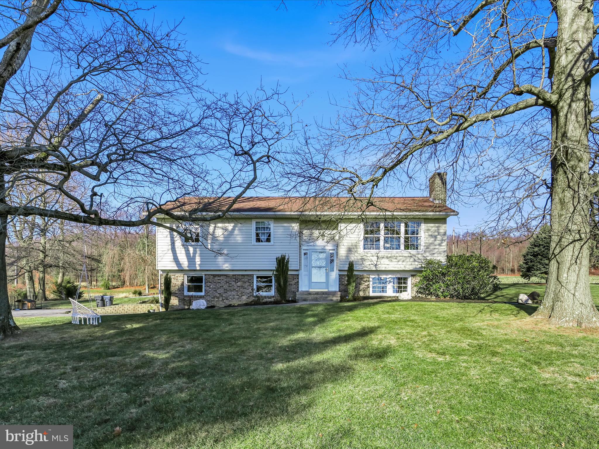 a view of a big house with a big yard plants and large tree