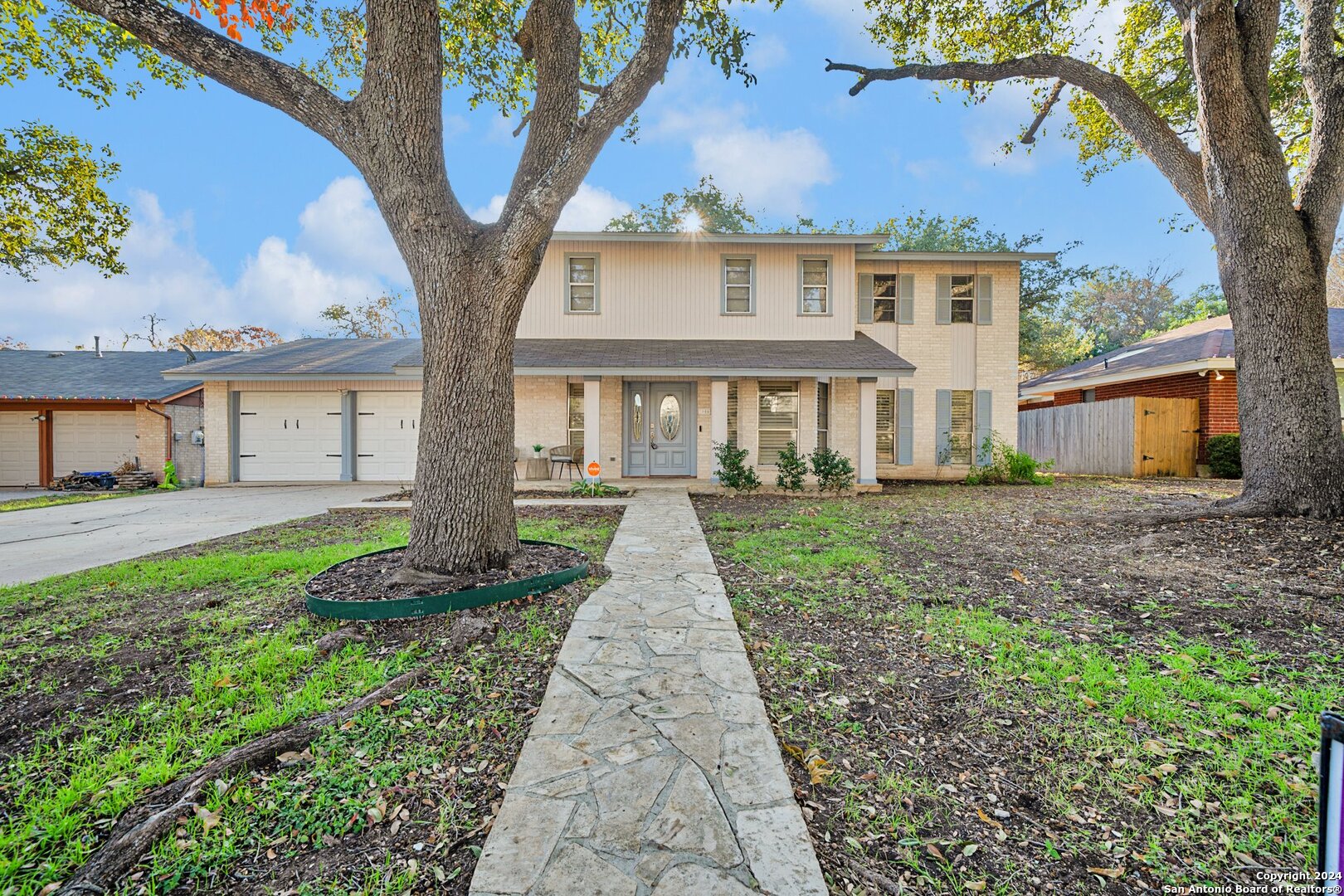 a front view of a house with a garden and trees