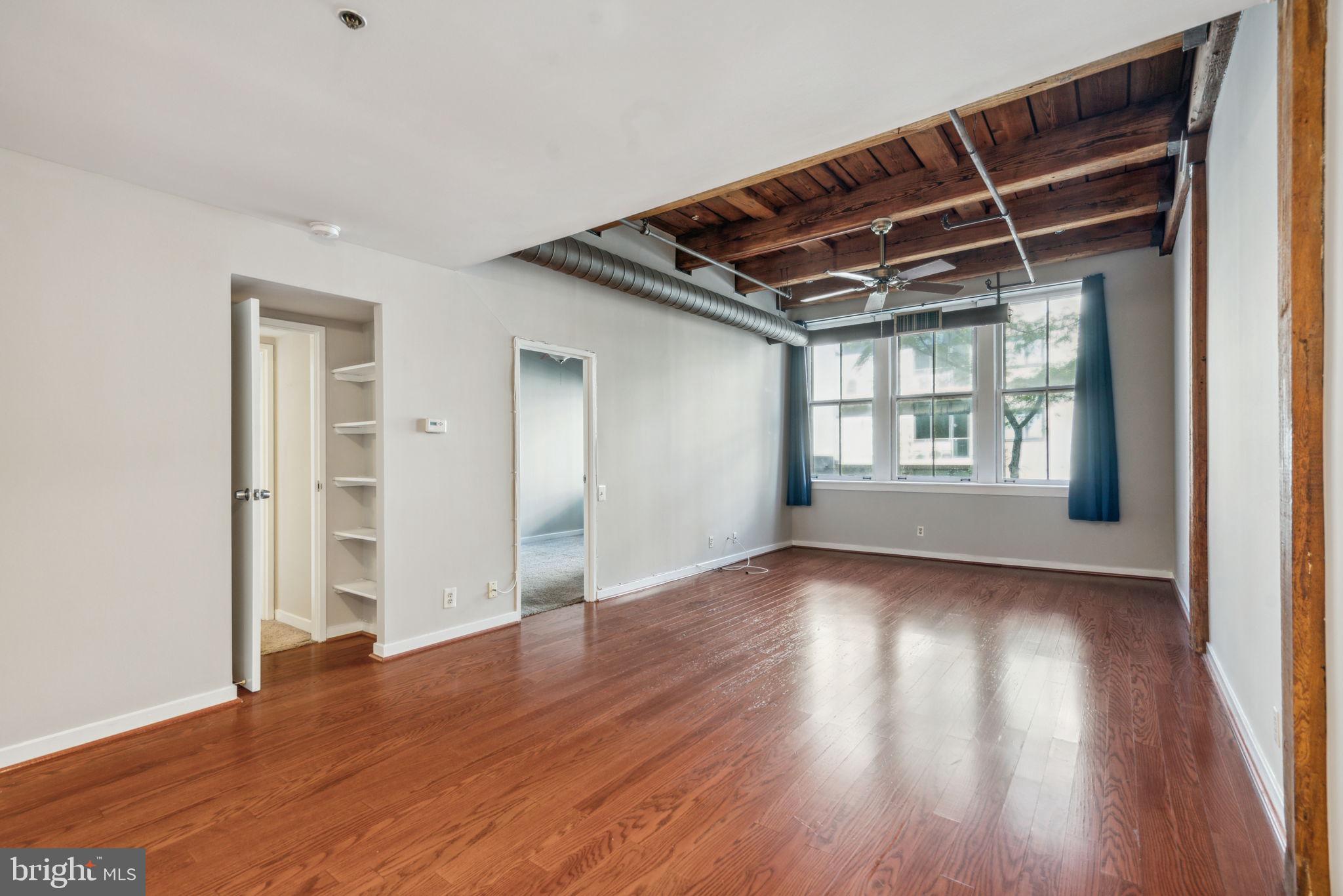 a view of an empty room with wooden floor and a window