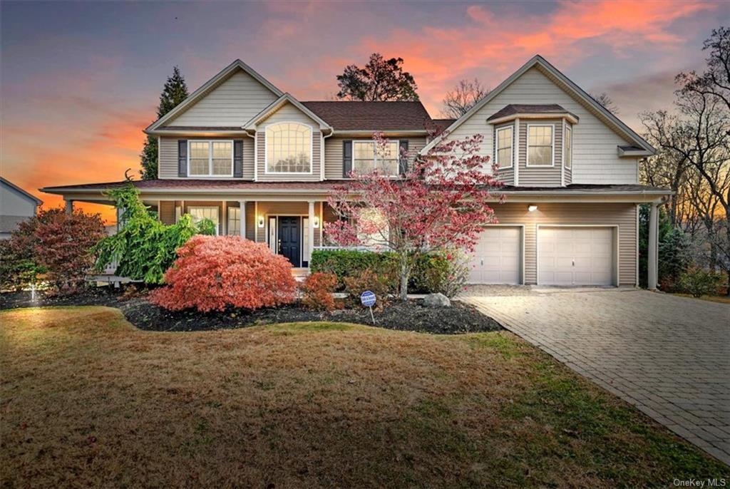 View of front of property with a lawn and a 2 attached garage with spacious driveway and mature landscape.