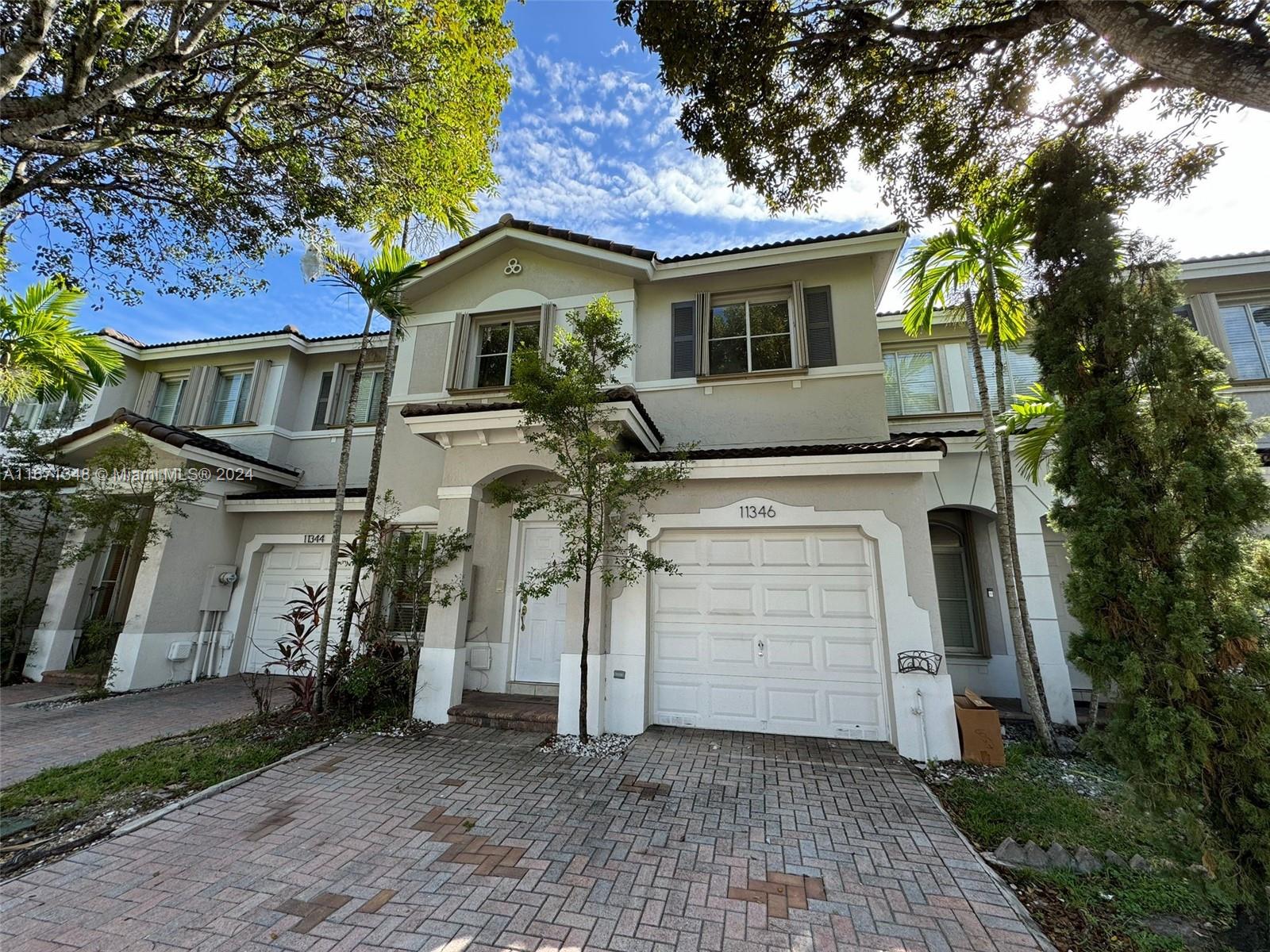 a view of a grey house with a small yard and large tree