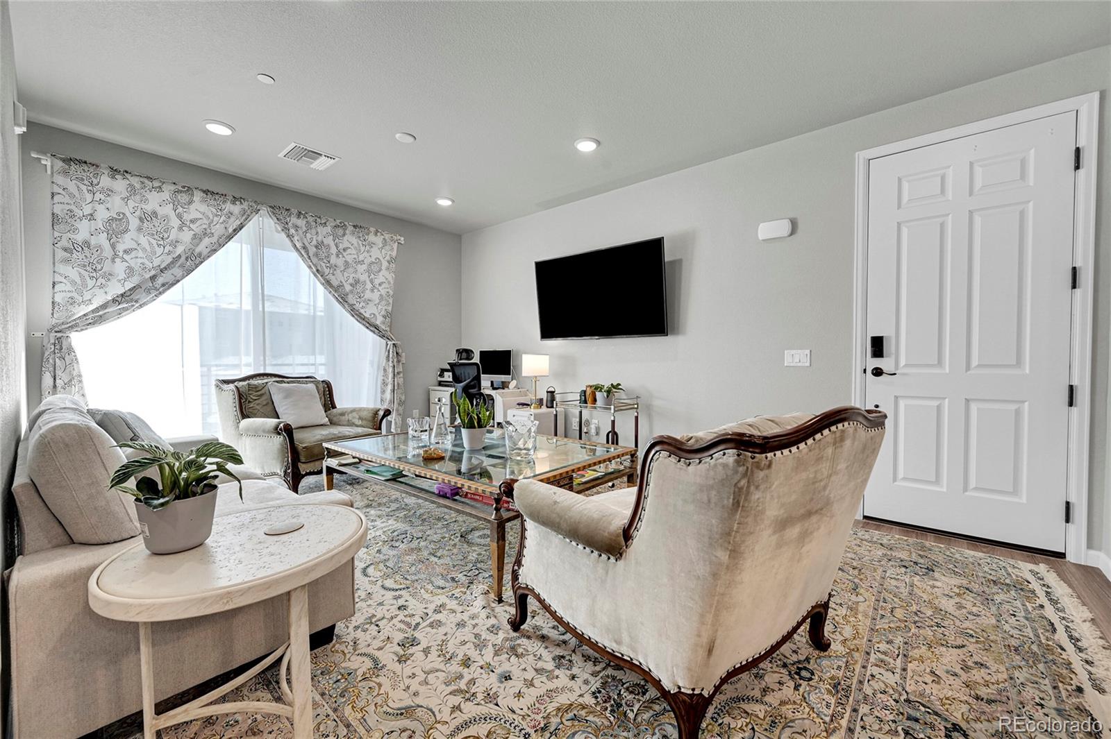 a living room with furniture a flat screen tv and a large window