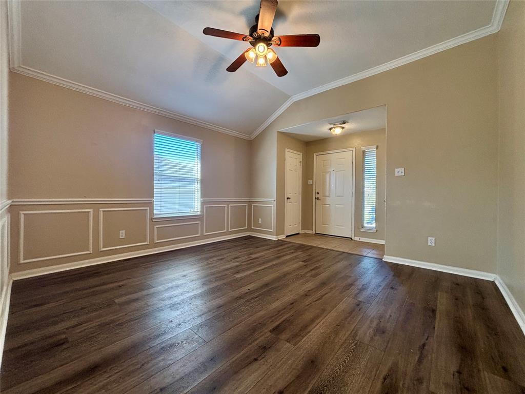 a view of an empty room with window and wooden floor