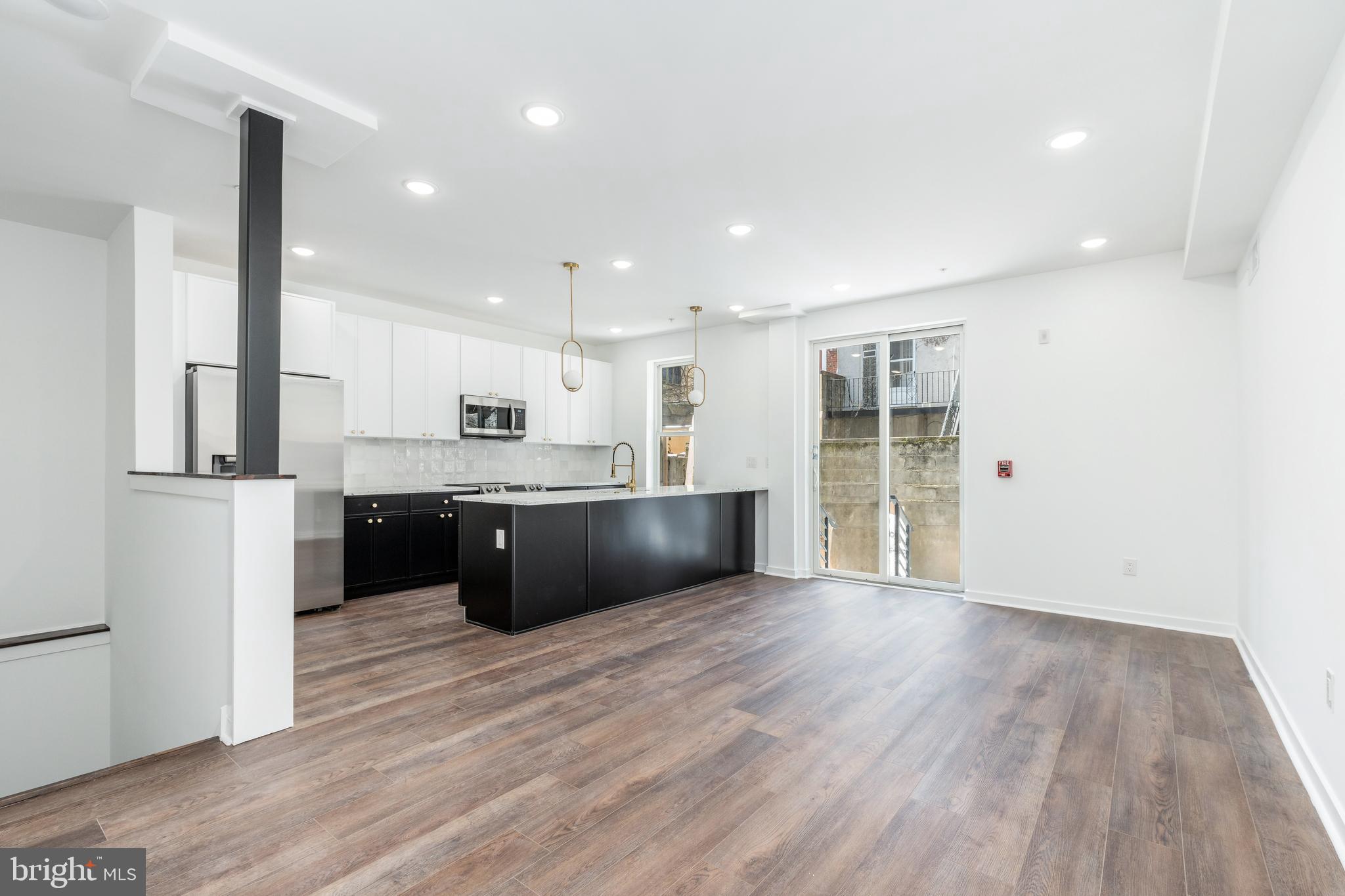 a large kitchen with a center island wooden floor and stainless steel appliances