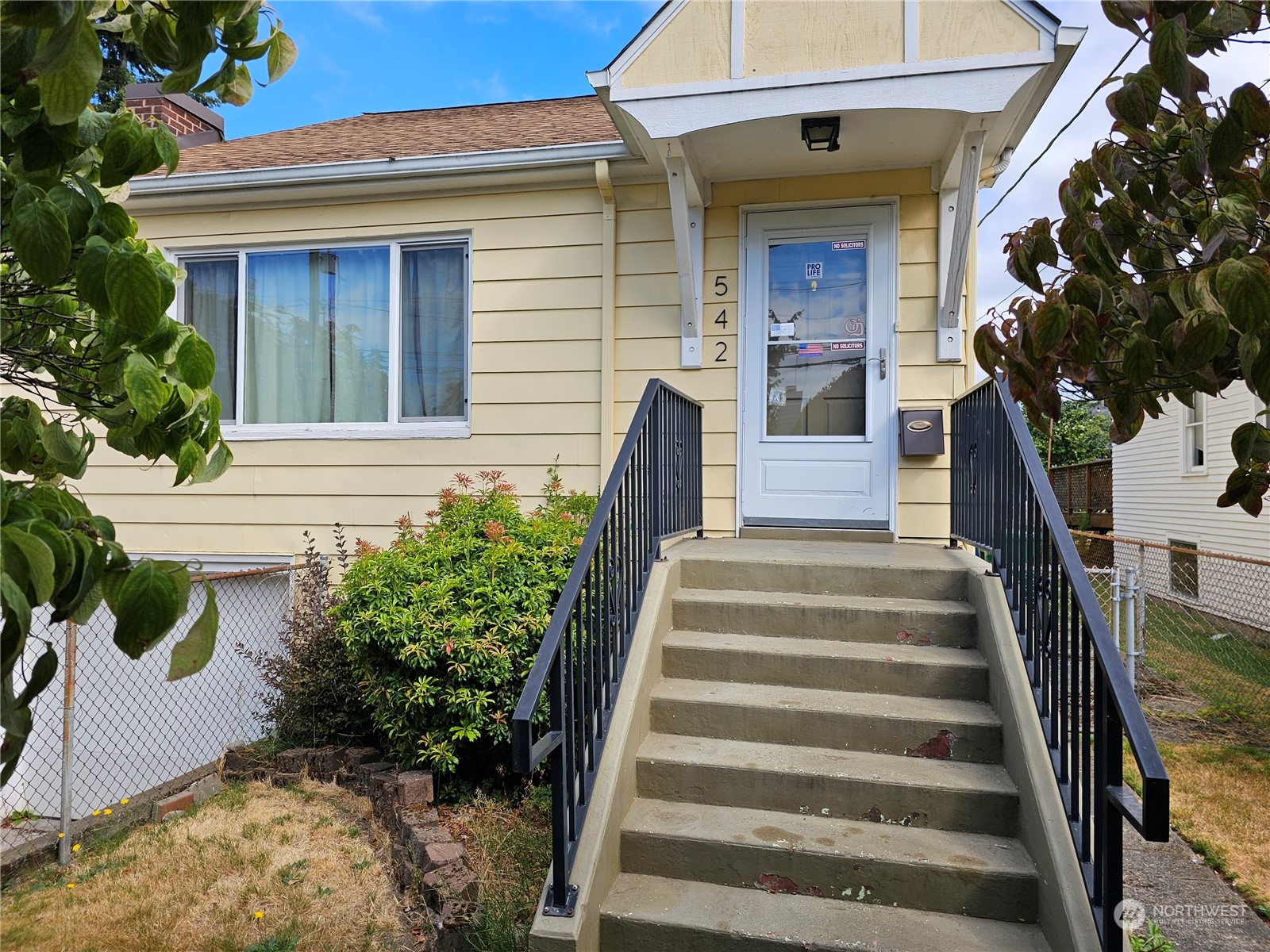 a front view of a house with potted plants and more windows