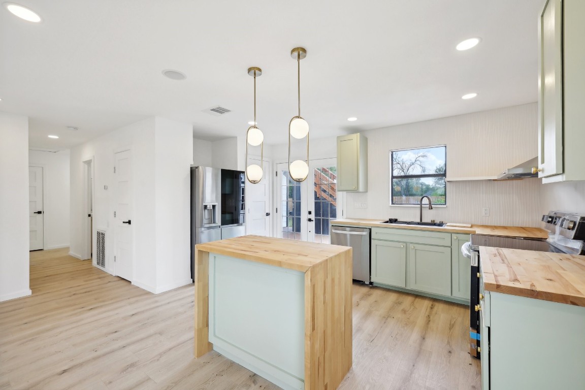 a large kitchen with kitchen island a stove a sink a center island and wooden floor