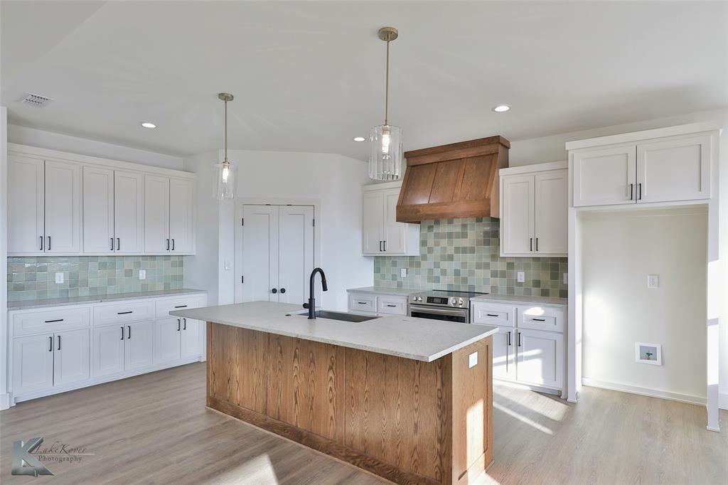 a kitchen with kitchen island granite countertop a sink a counter space and cabinets