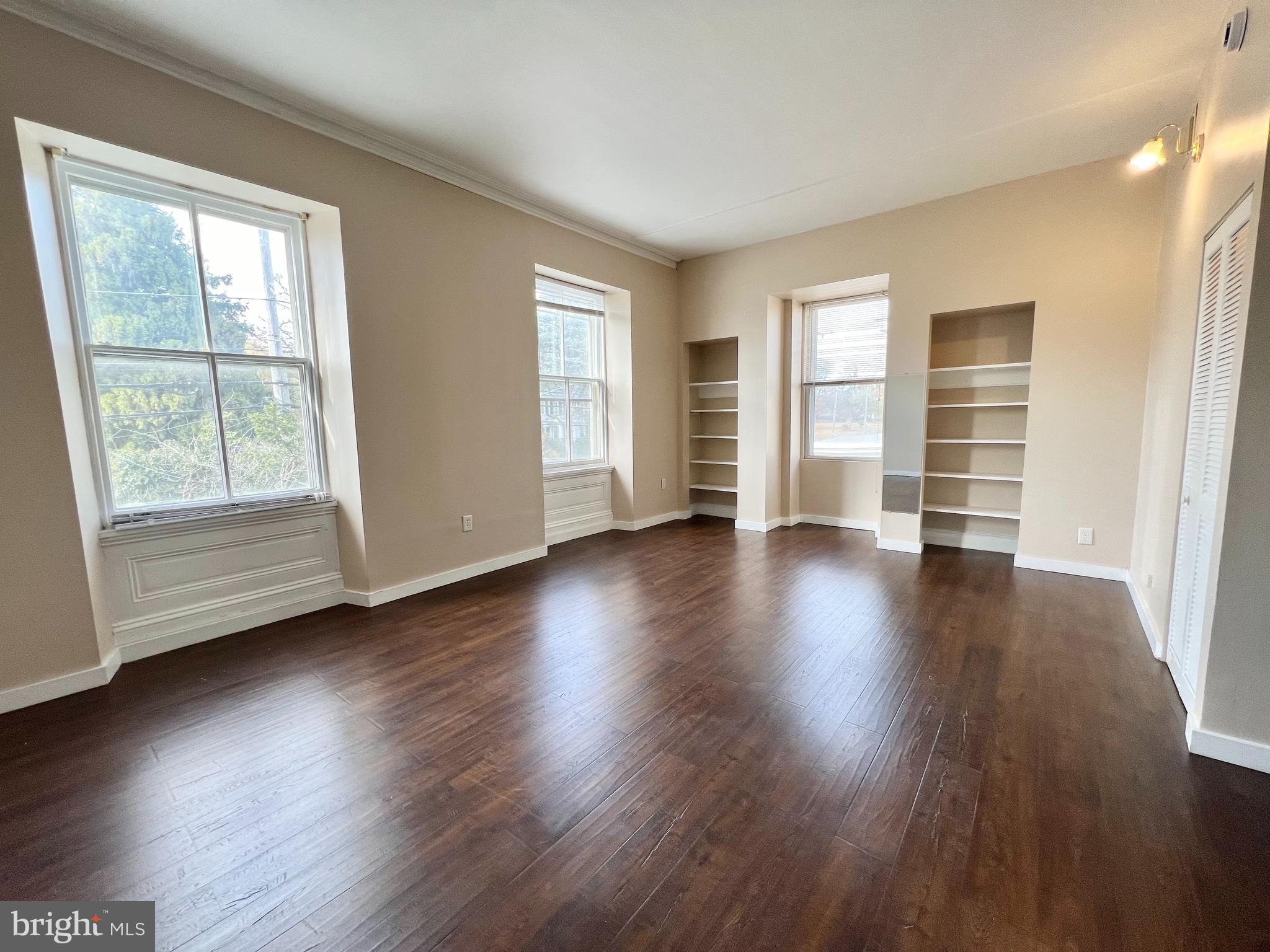 an empty room with wooden floor and windows