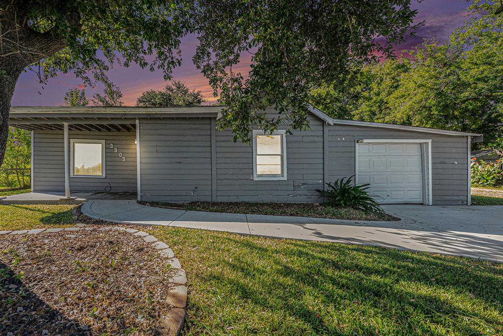 Welcome to this charming home, boasting a serene facade complemented by lush landscaping and a sweeping driveway leading to an attached garage, all set against a backdrop of a picturesque sunset sky.