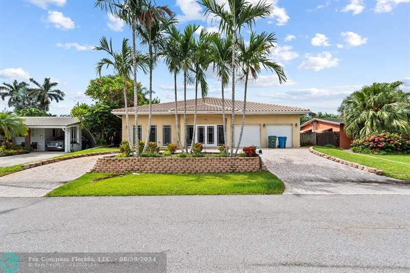 front view of house with a yard and palm trees