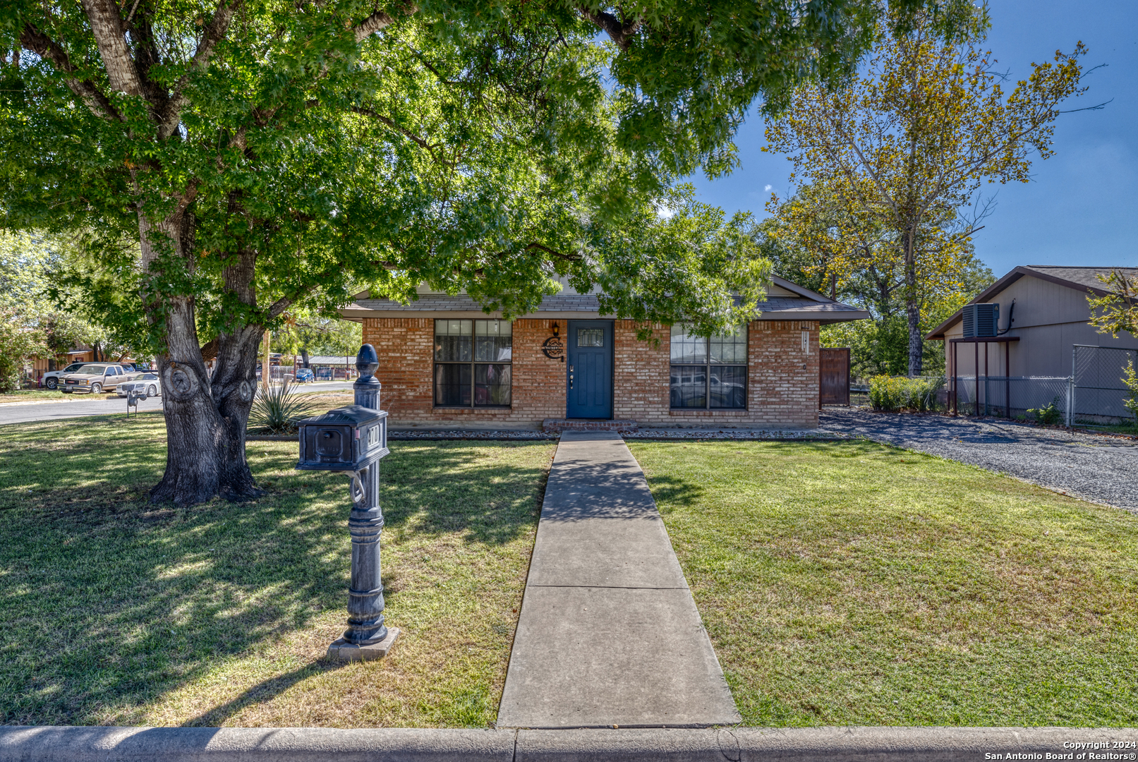 a front view of a house with a yard and a large tree