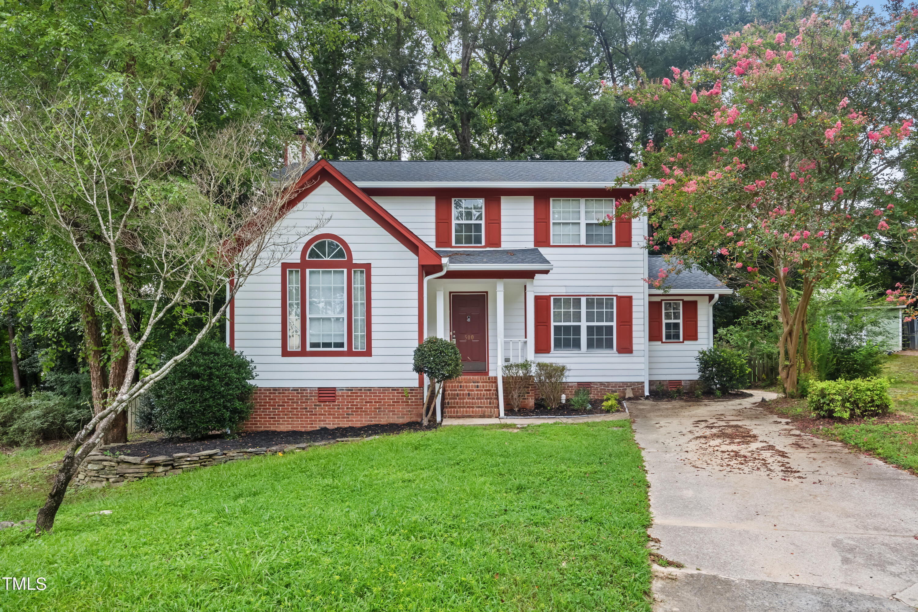 a front view of a house with a garden and trees