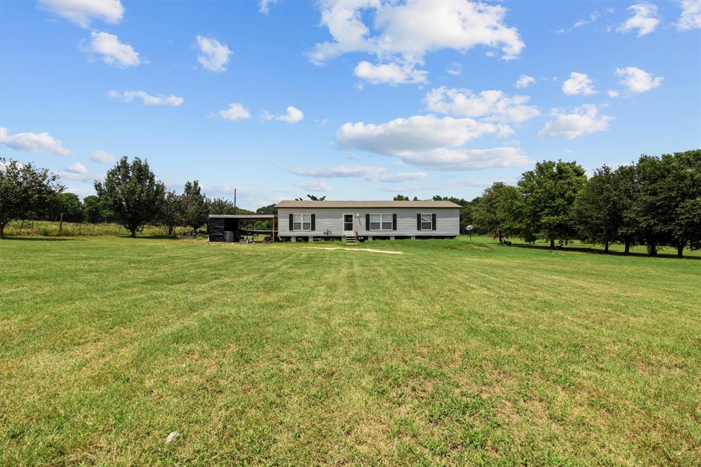 a view of a green field with house in the background