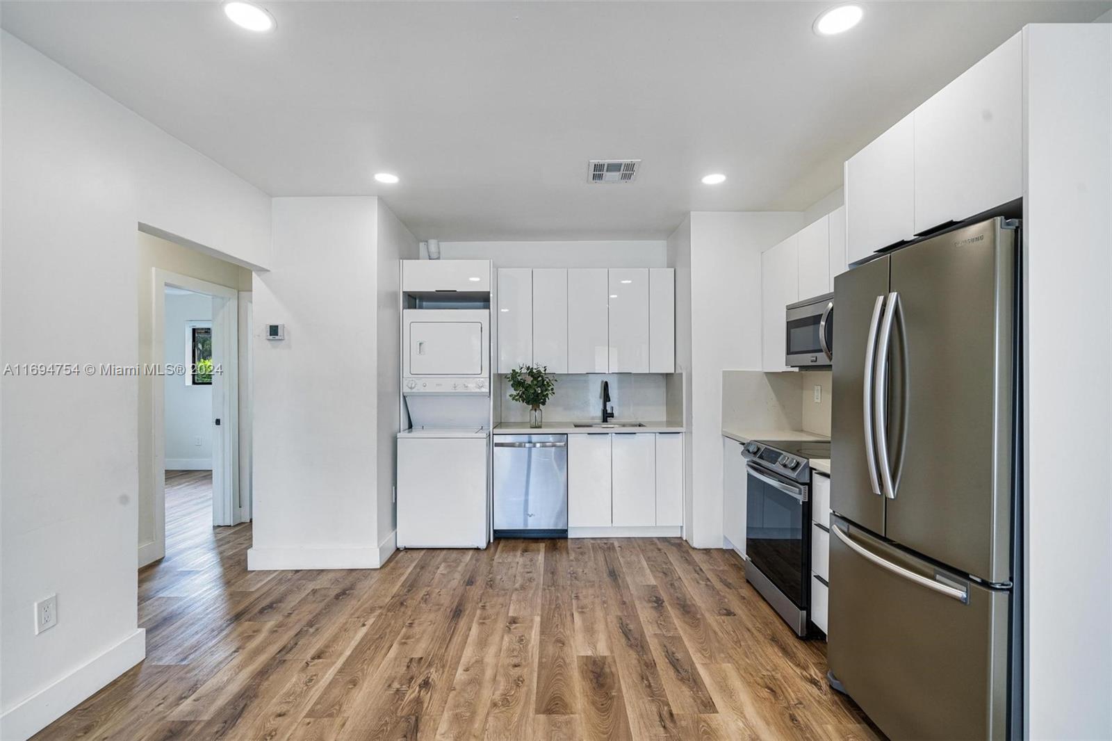 a kitchen with a refrigerator stainless steel appliances wooden floor and a window