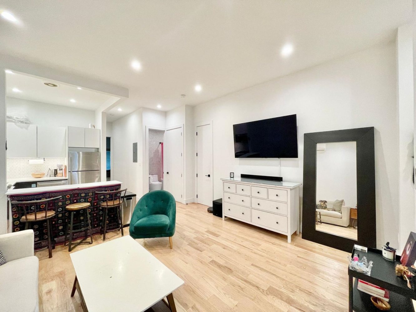 a living room with furniture a flat screen tv and kitchen view