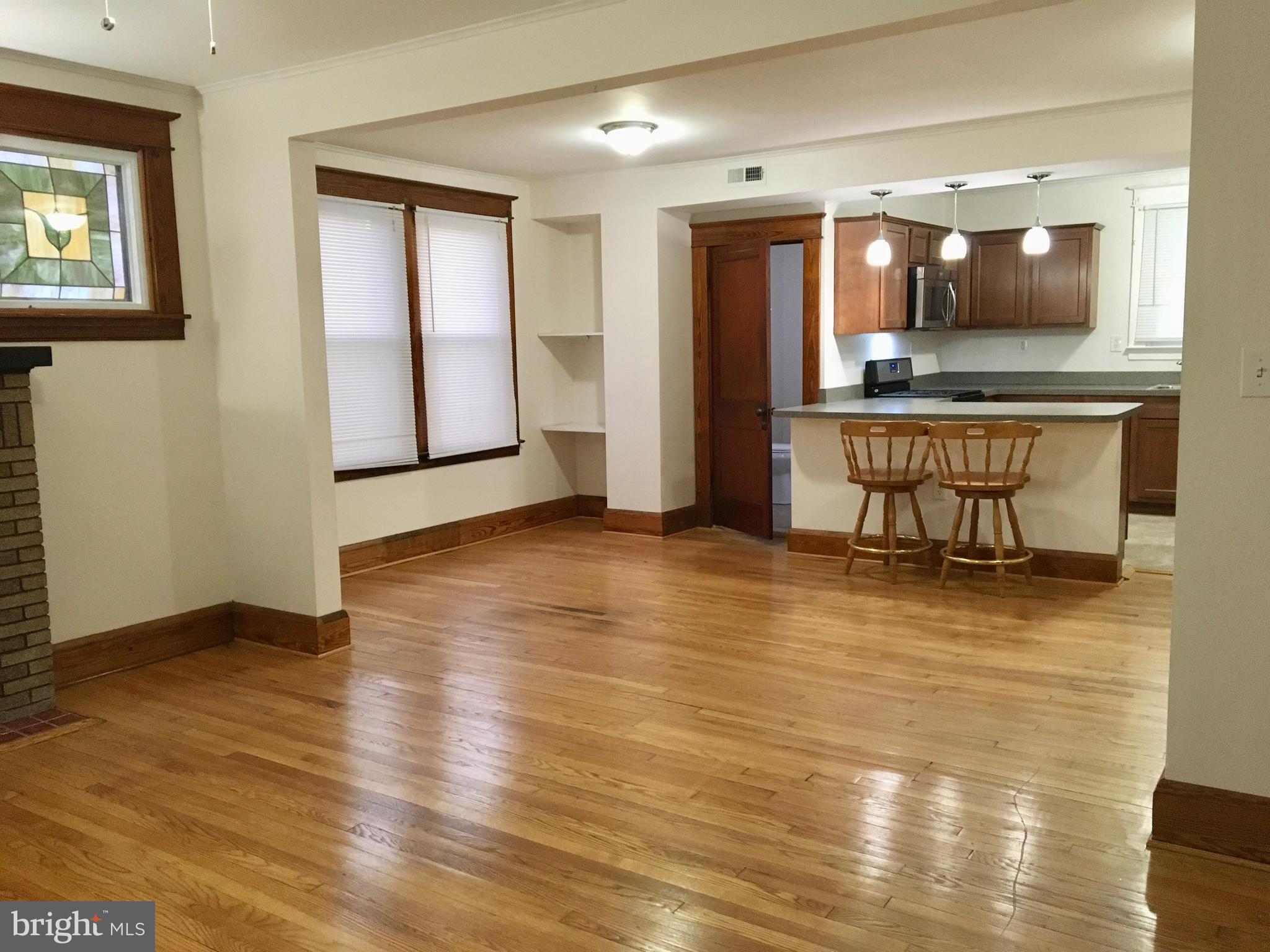 an empty room with wooden floor and kitchen view