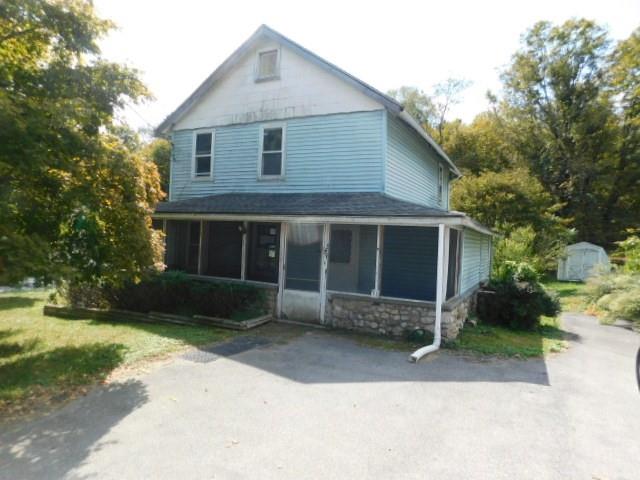 View of front of home with a sunroom and a shed