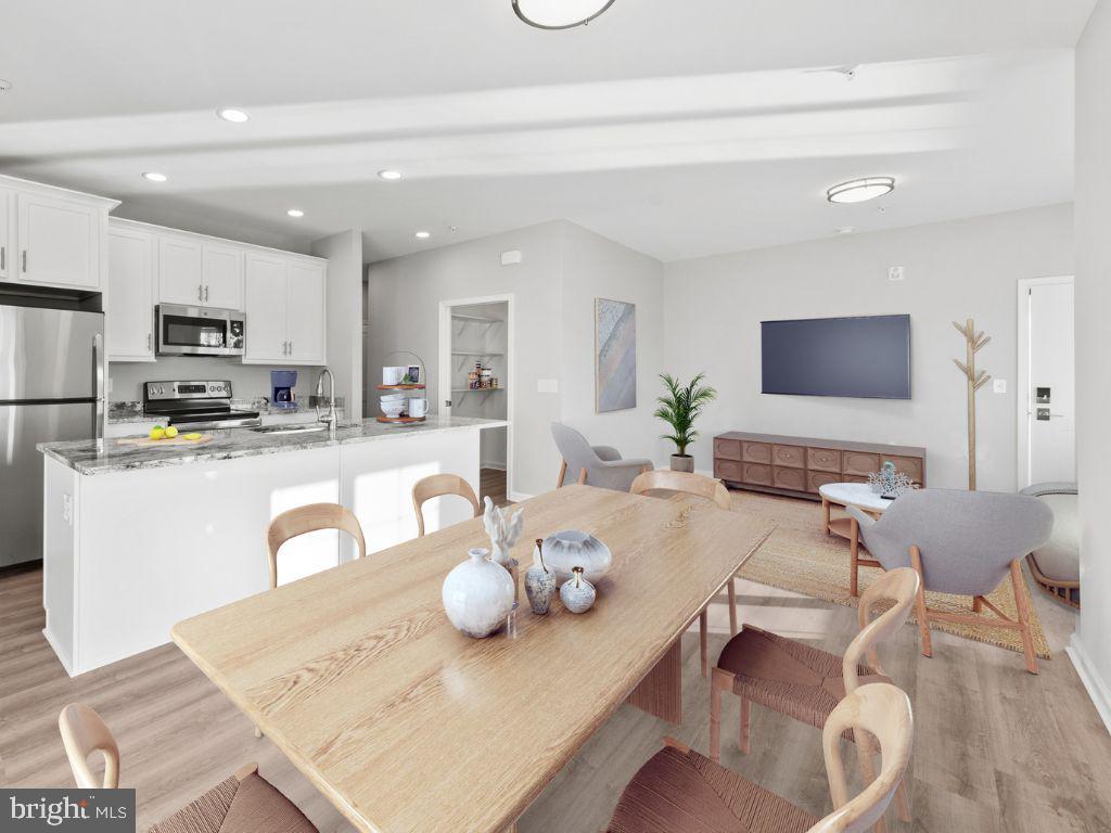 a living room with stainless steel appliances furniture a dining table and chairs