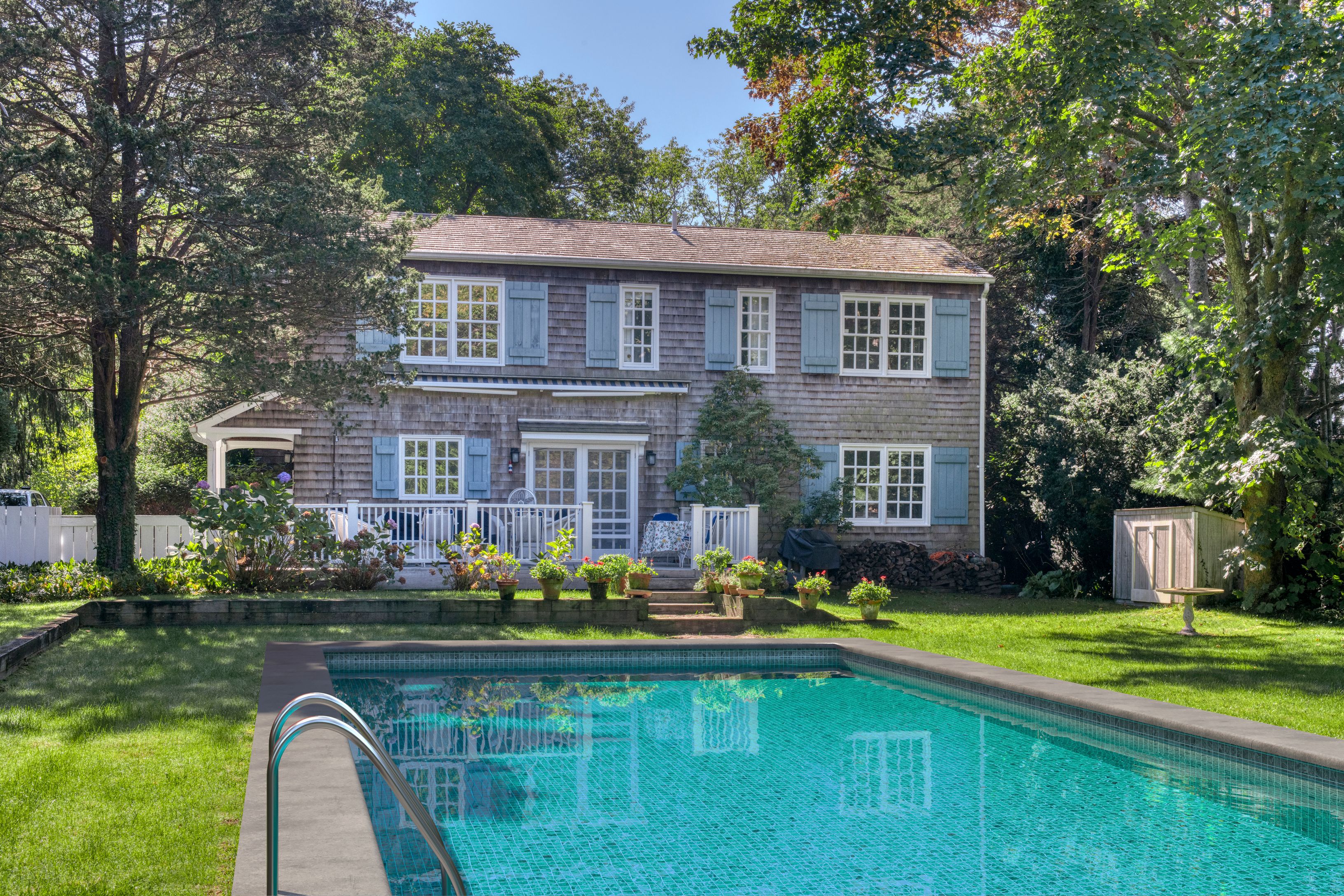 a front view of a house with swimming pool lawn chairs and a yard