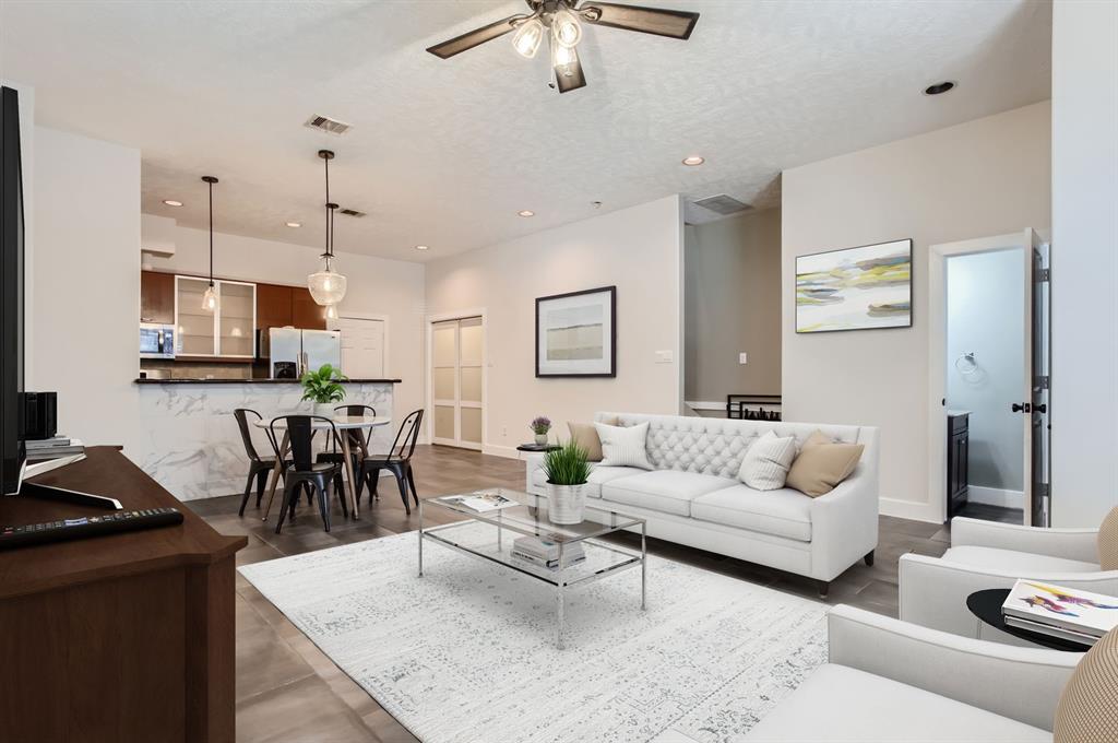 a living room with furniture kitchen view and a chandelier