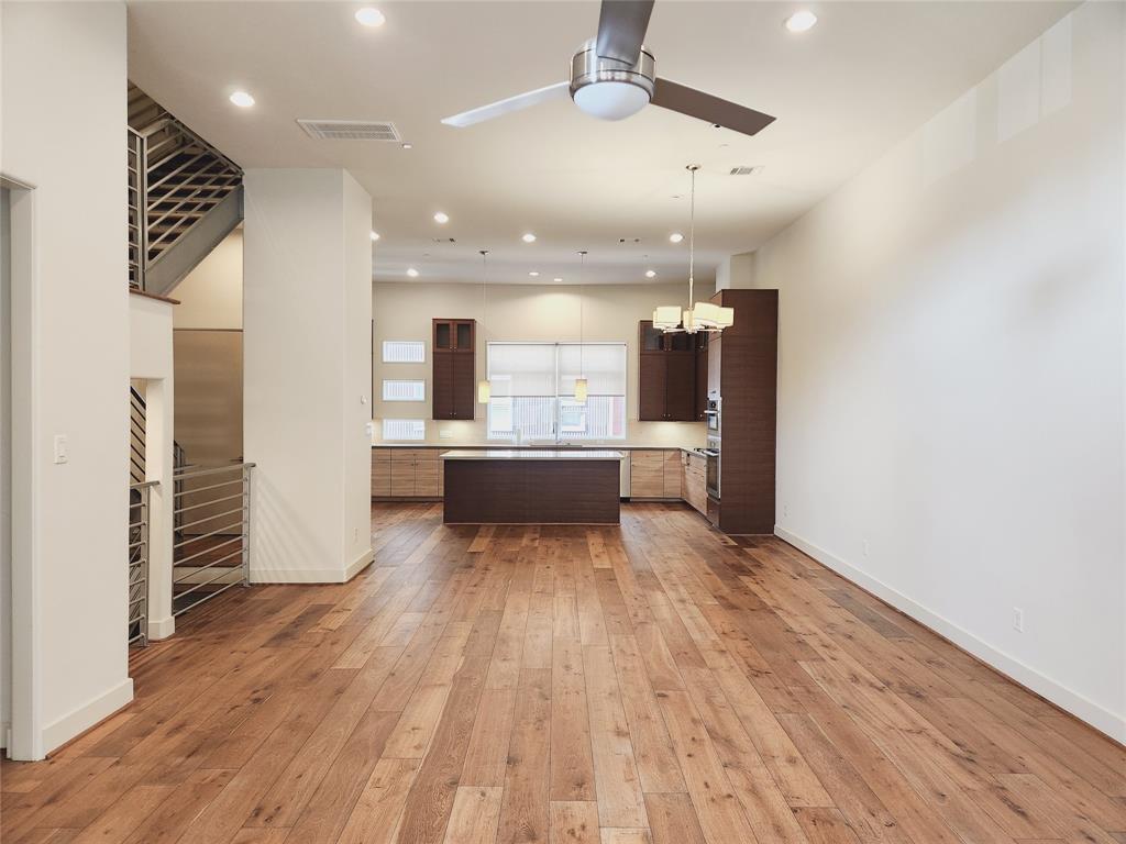 an empty room with wooden floor and kitchen