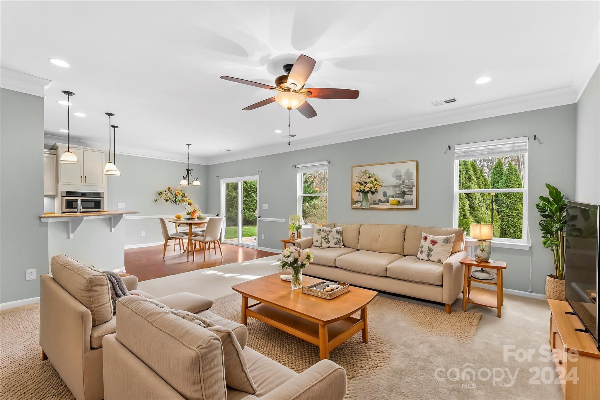 a living room with furniture ceiling fan and a large window