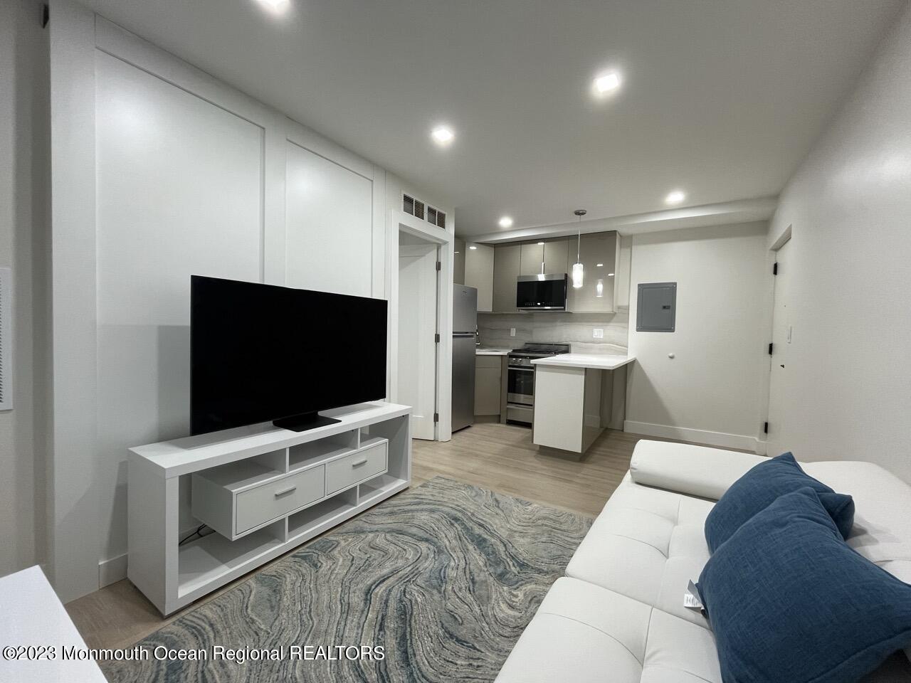 a living room with stainless steel appliances furniture and a flat screen tv