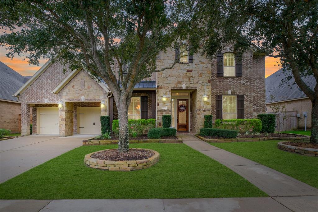 a front view of a house with a yard and green space