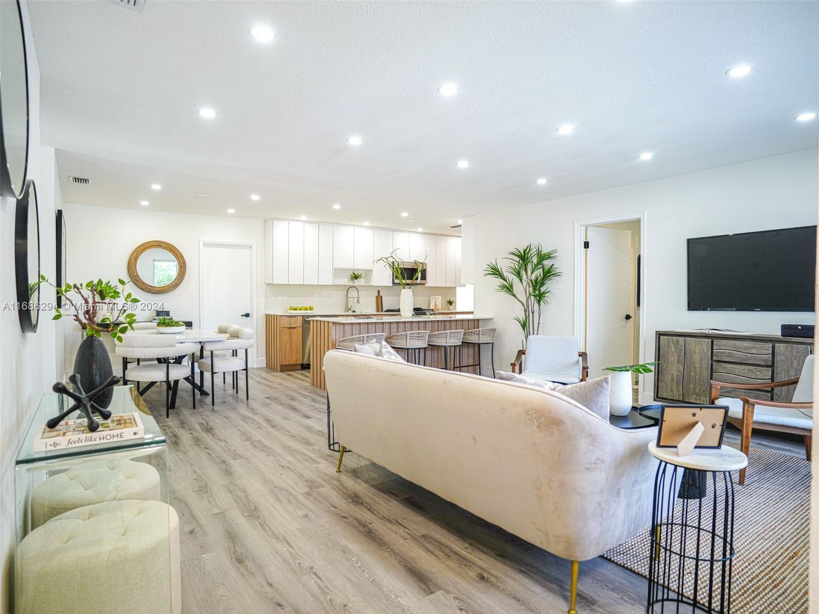 a living room with furniture kitchen view and a large window