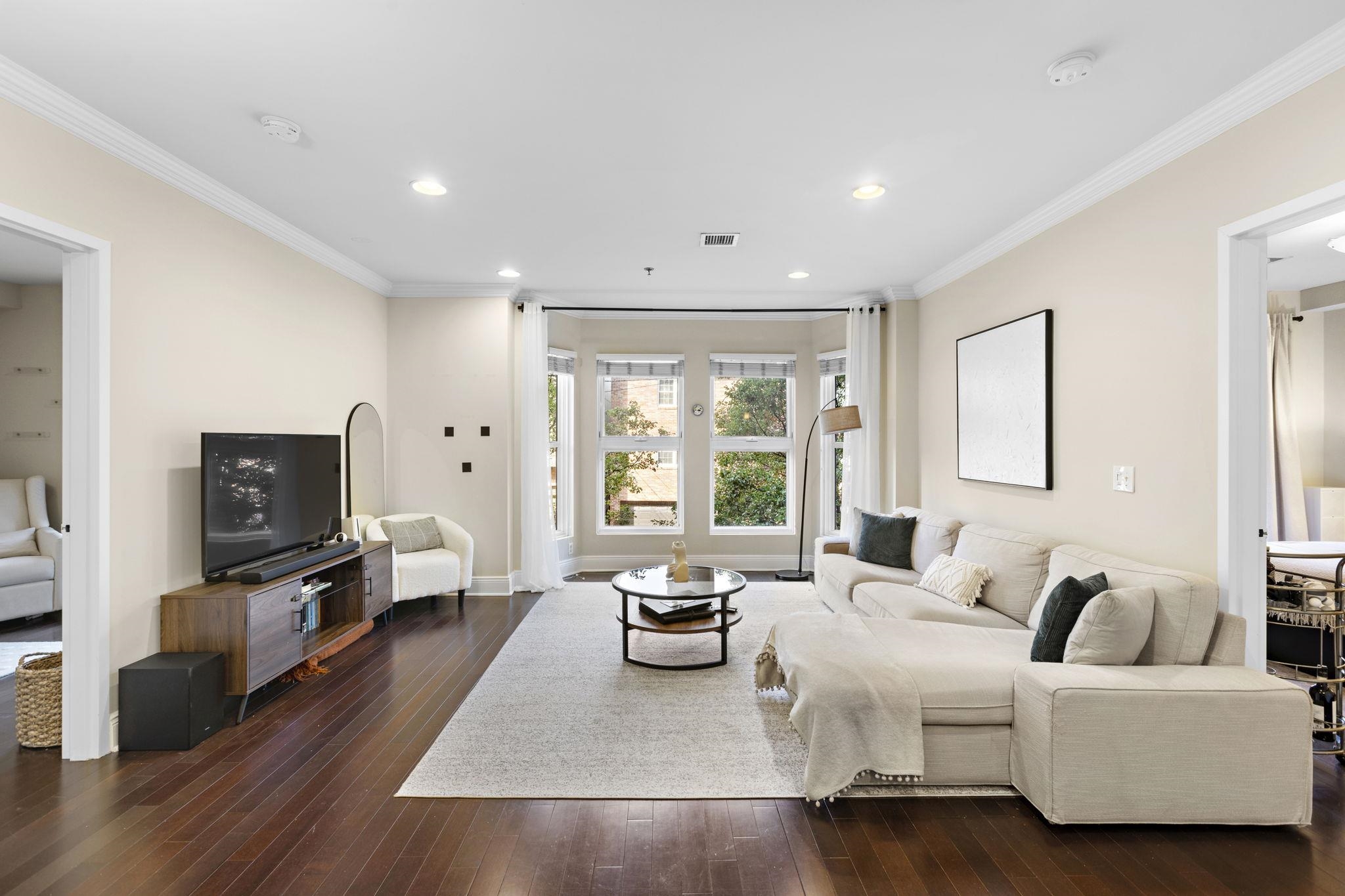 a living room with furniture flat screen tv and a large window