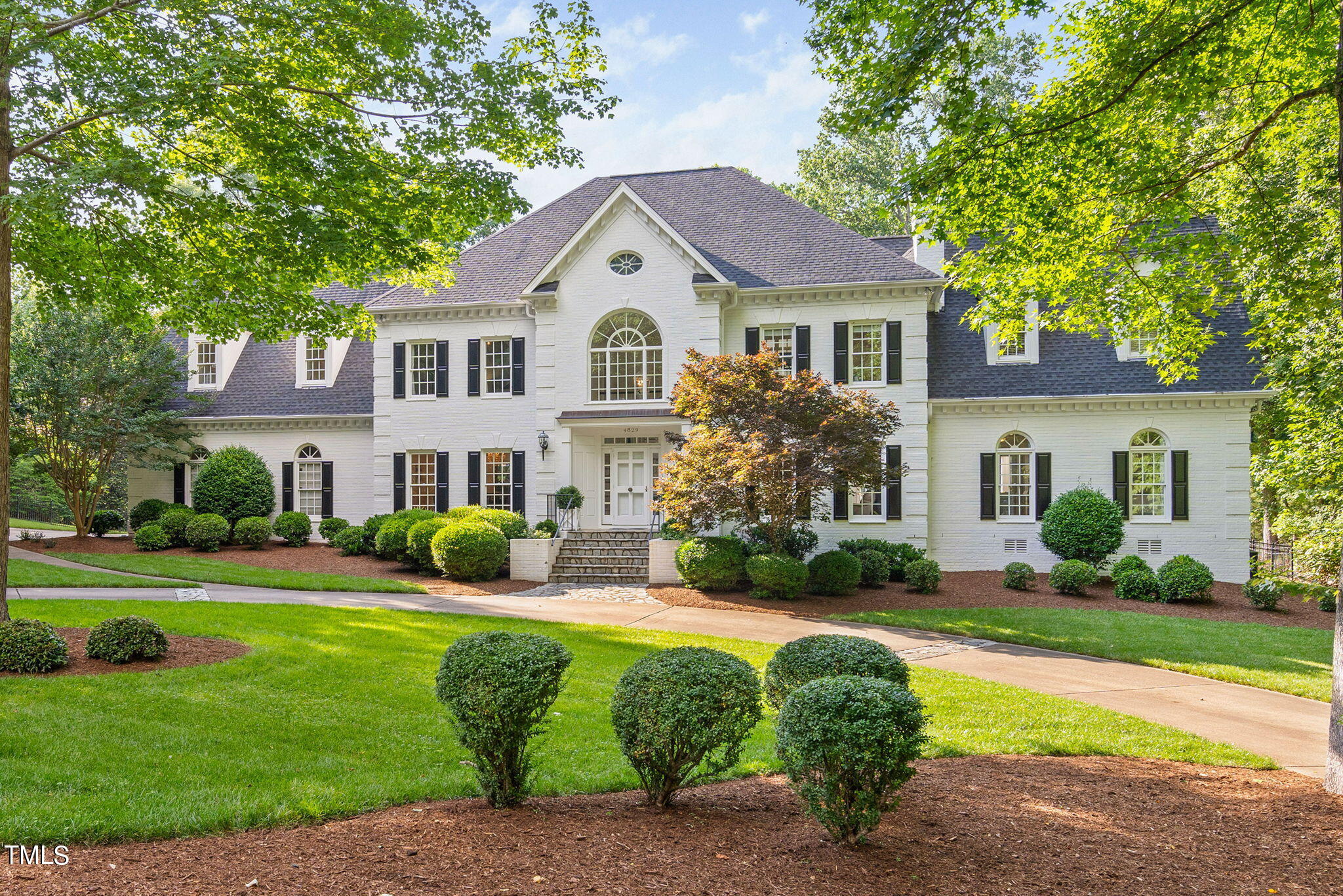 a front view of a house with garden and trees