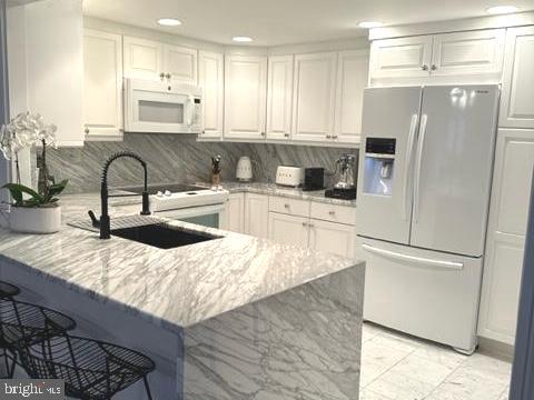 a kitchen with stainless steel appliances granite countertop a refrigerator a sink and white cabinets