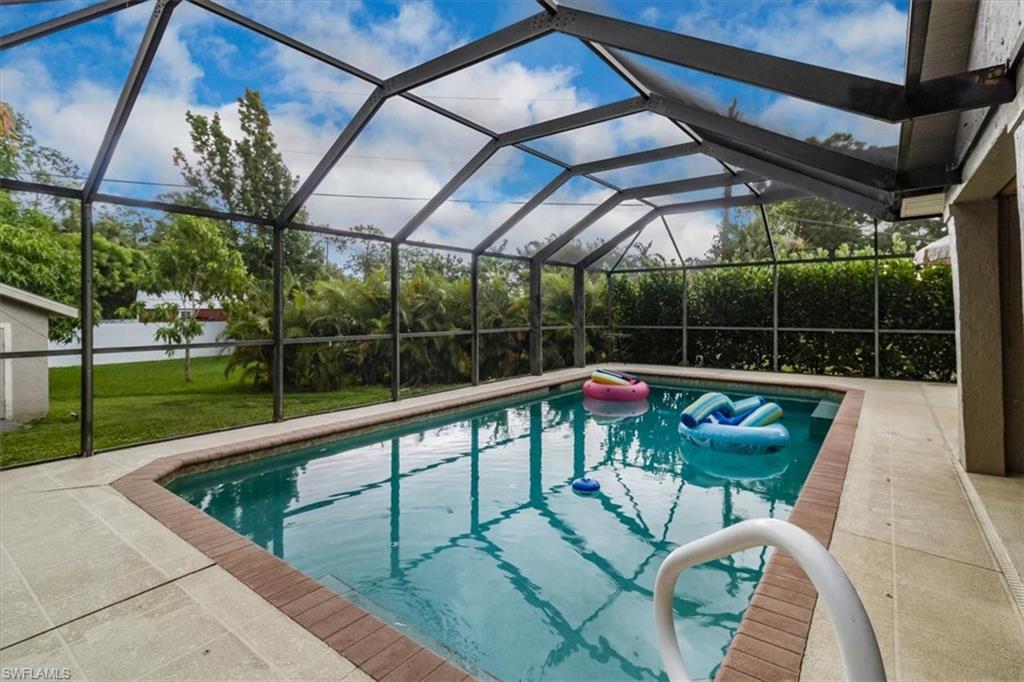 a view of swimming pool with a couches and chairs under an umbrella