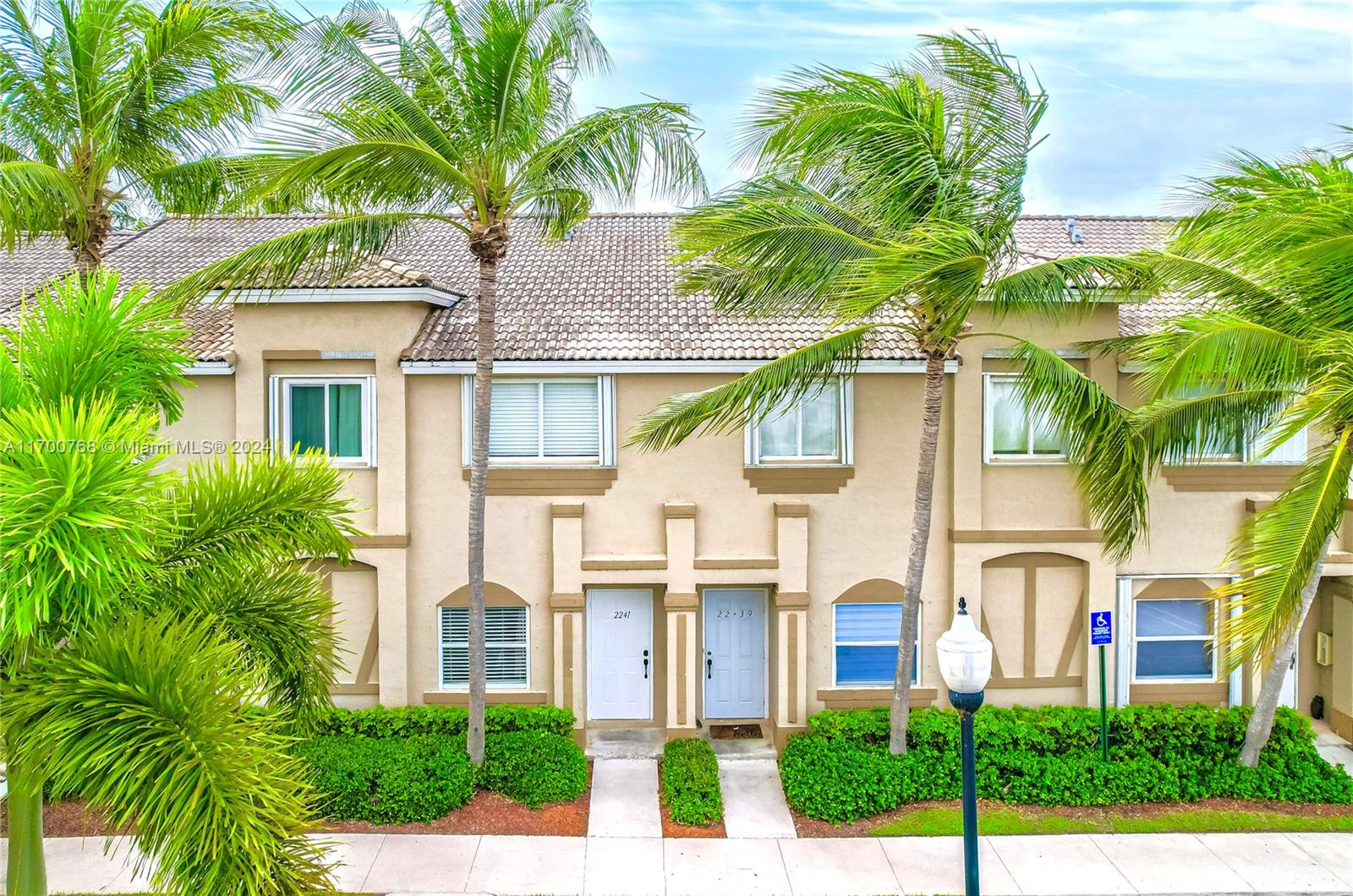 a front view of white house with a palm tree