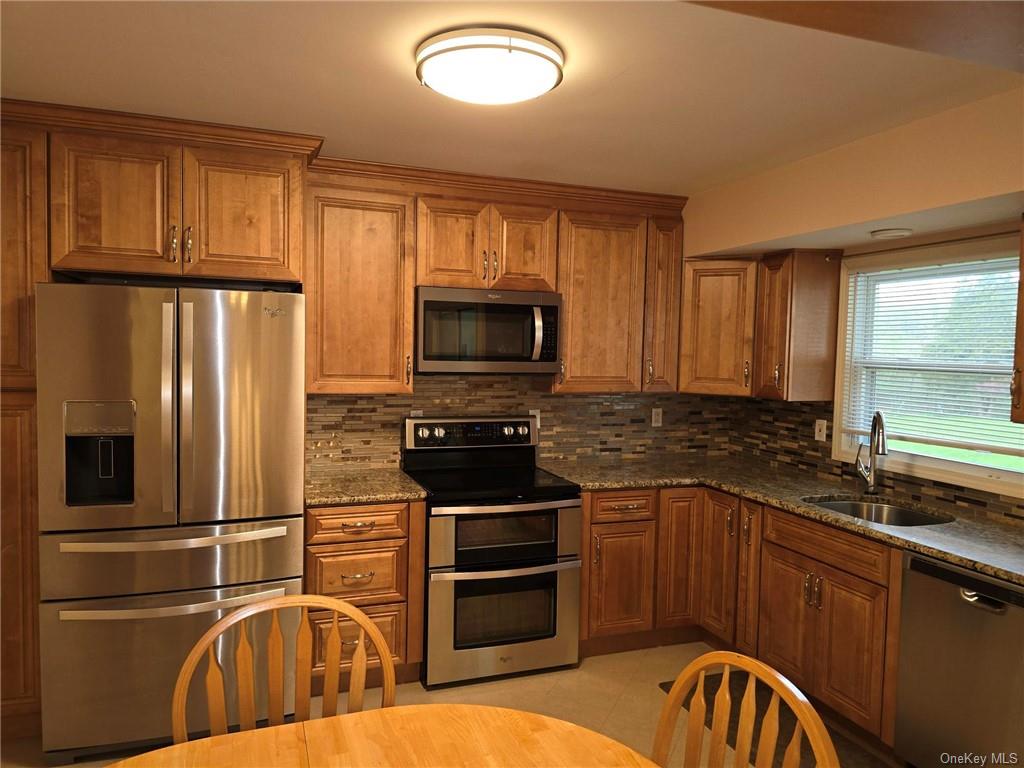 a kitchen with granite countertop a refrigerator stove and microwave