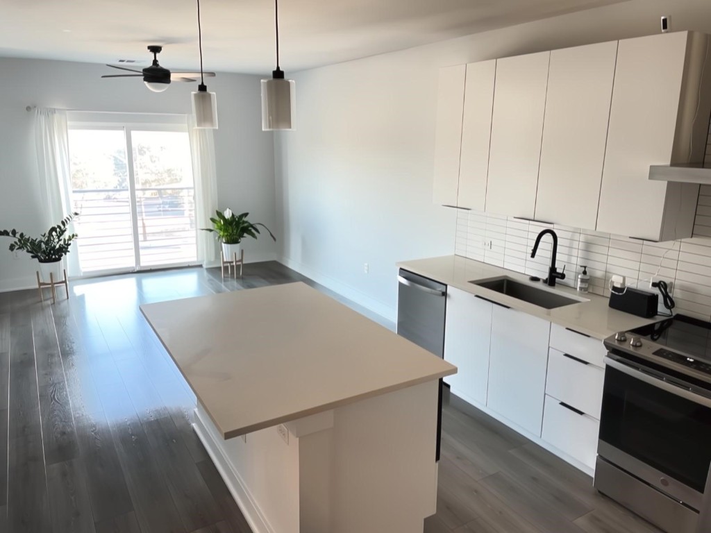 a kitchen with a sink a stove cabinets and wooden floor