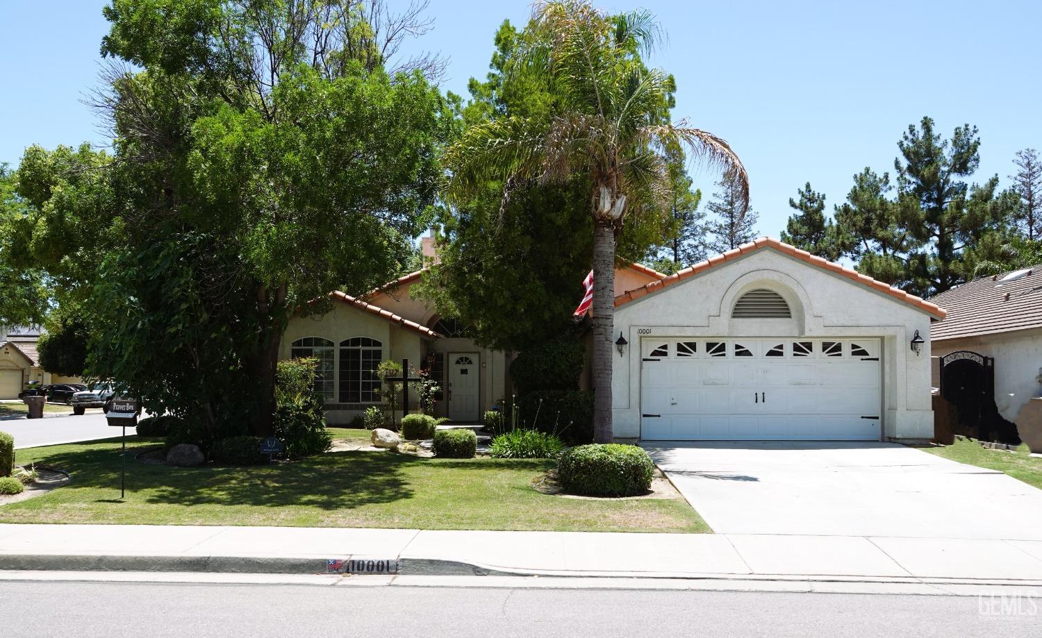 a view of house with a yard and large trees