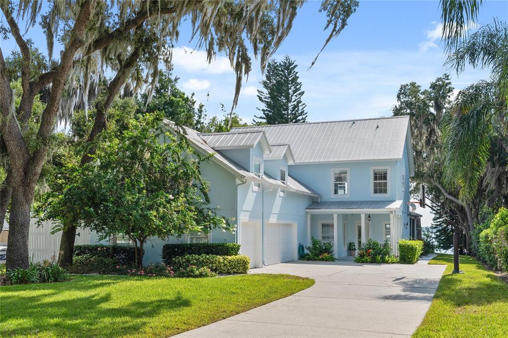 a view of a white house next to a yard with palm trees