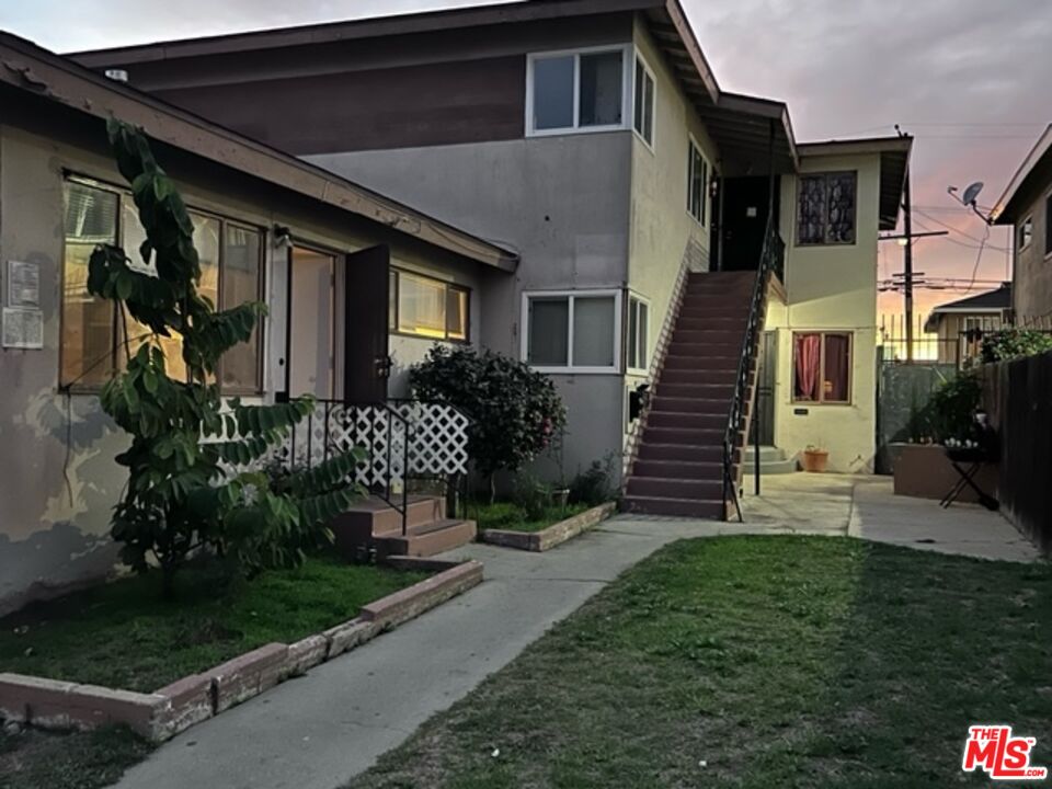 a view of a house with a small yard plants and large tree