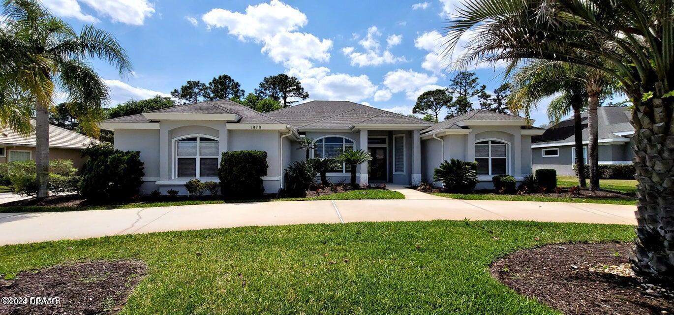 a view of a house with a yard and palm trees