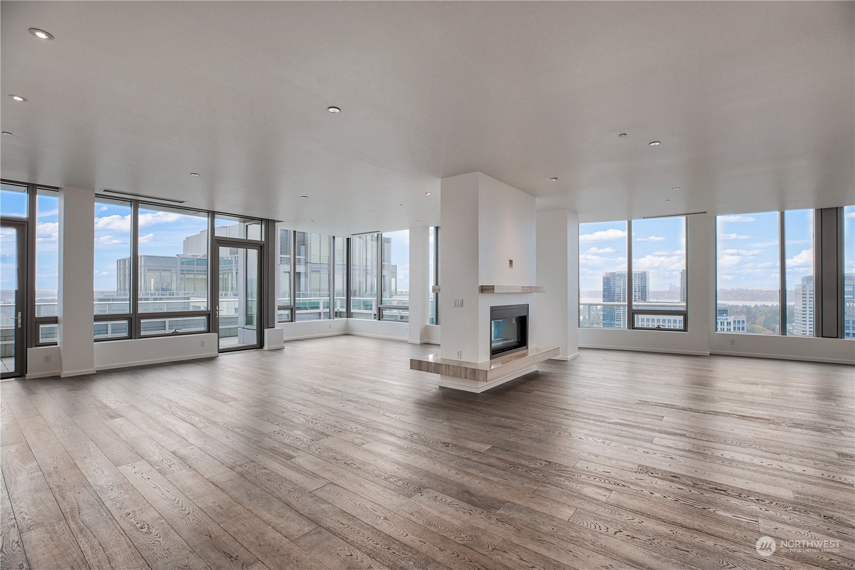 a view of an empty room with wooden floor and a fireplace